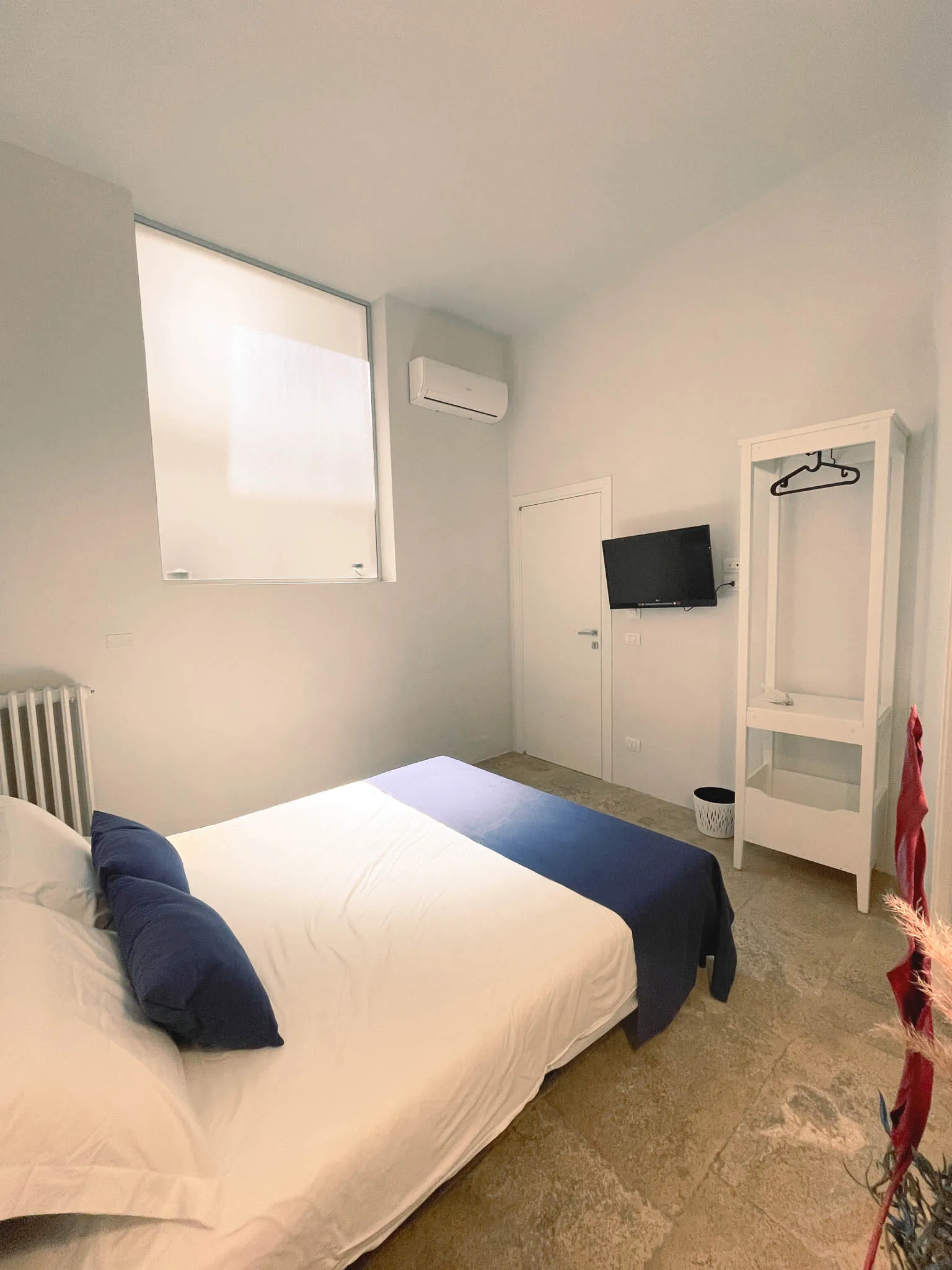 La camera Pètra vista dall’ingresso: letto, televisore a parete, finestra e condizionatore