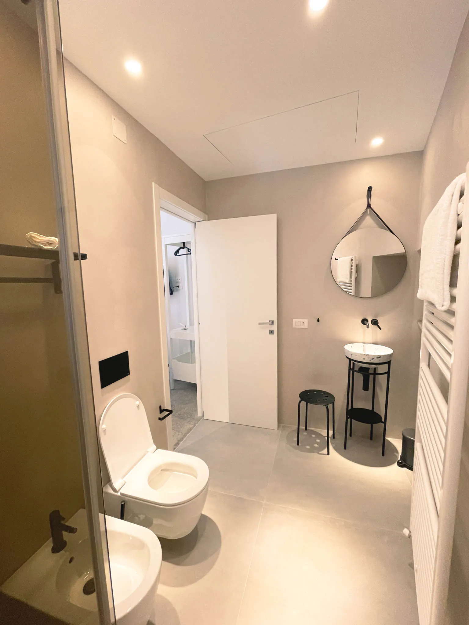 Il bagno della camera Pètra: specchio tondo sopra il lavabo, wc, bidet e box doccia