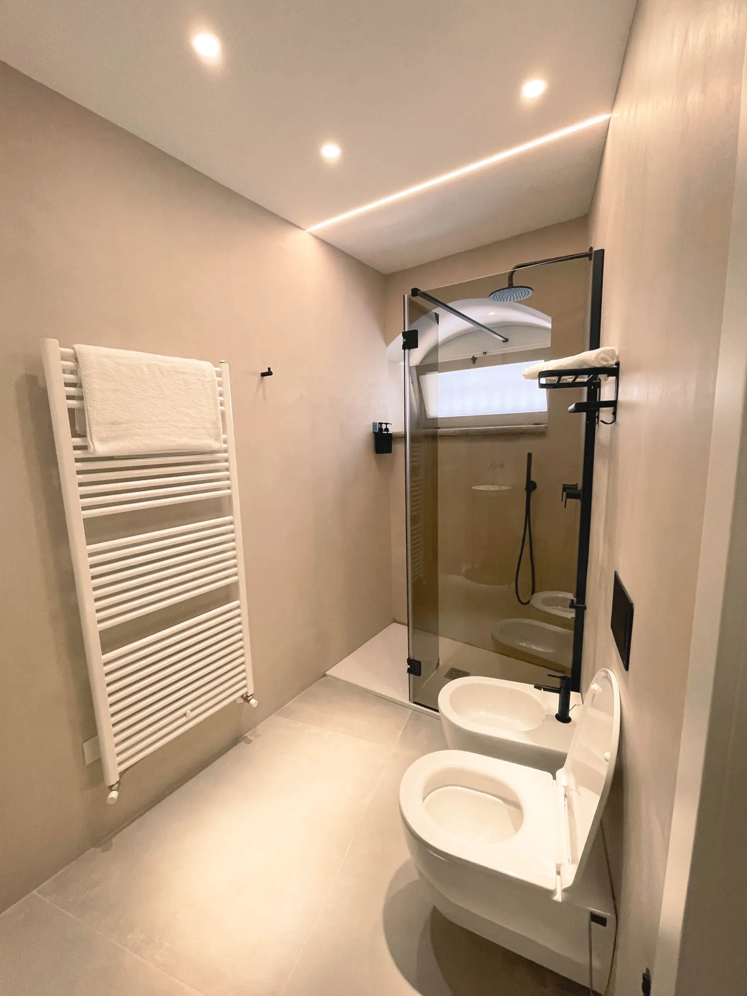Il box doccia in vetro del bagno della camera Pètra accanto al termoarredo a scala