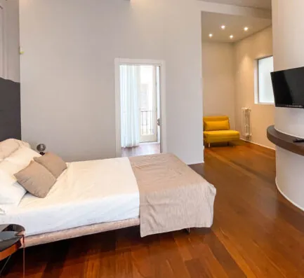 La camera Xylo: letto matrimoniale e pavimento in legno scuro, con la parete curva sullo sfondo