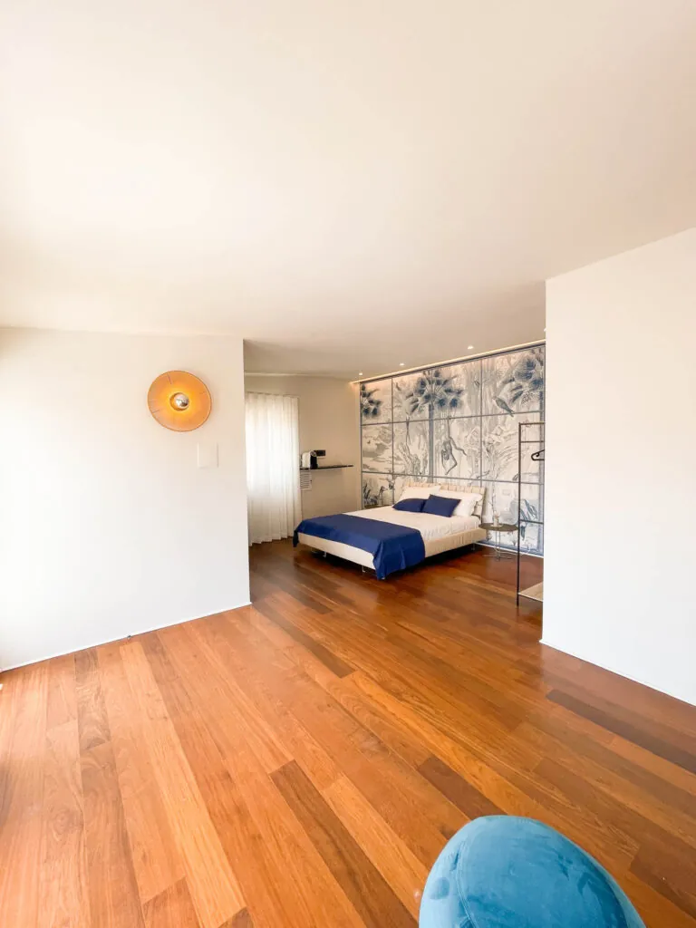 La camera Fos vista dall’ingresso: pavimento in legno, pouf azzurro e vetrata decorata