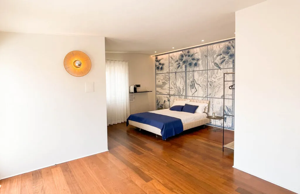 Camera matrimoniale con parete decorata a motivi floreali e pavimento in parquet