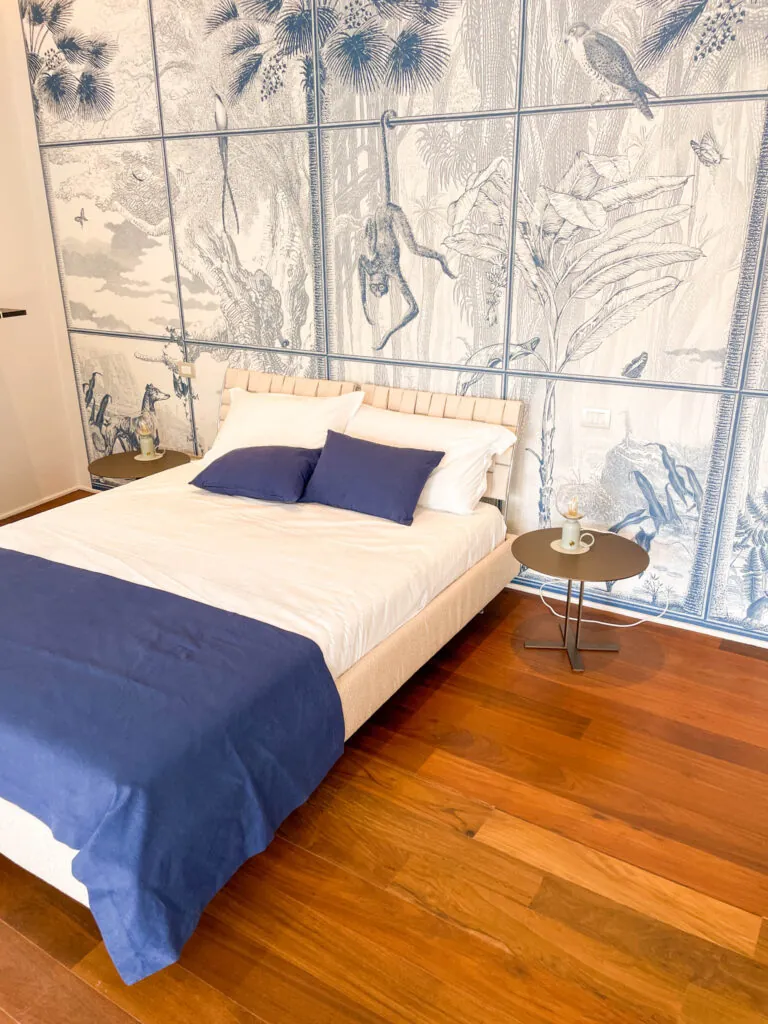 Il letto della camera Fos davanti alla vetrata decorata a motivi floreali