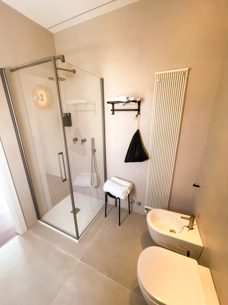 Il box doccia in vetro del bagno della camera Fos accanto al termoarredo