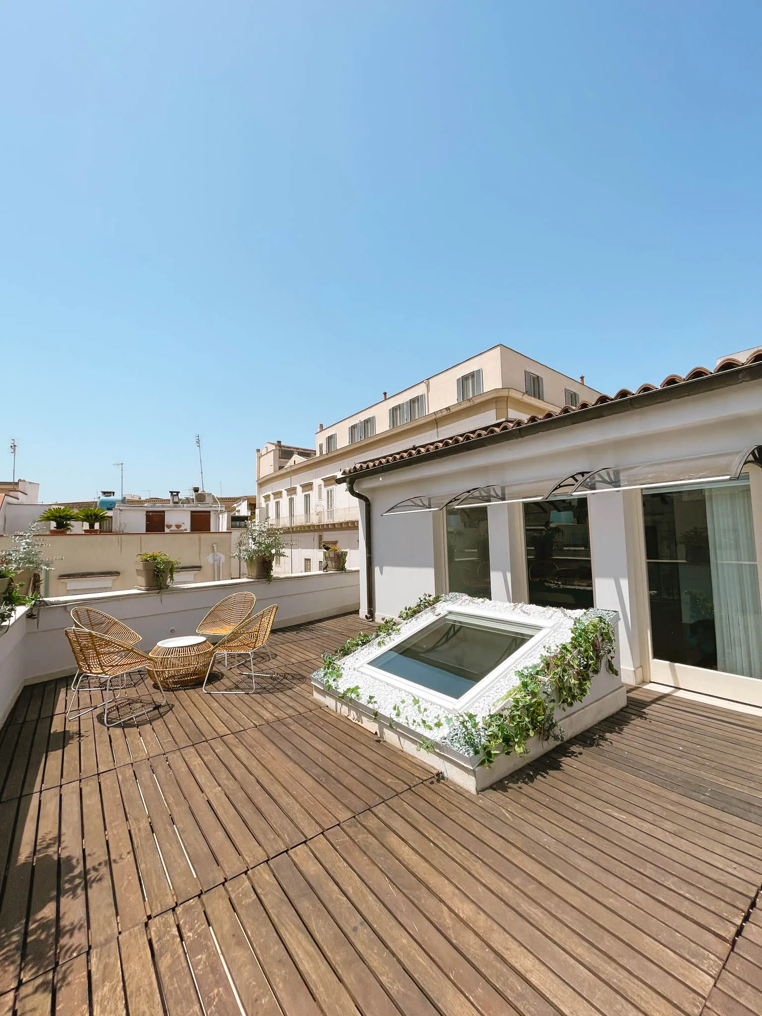 Terrazza in legno con poltroncine in rattan e vista sui tetti di Andria