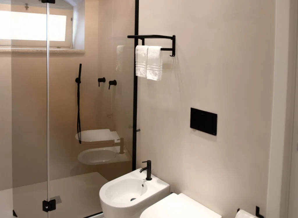 Bagno con doccia in vetro, rubinetteria nera e portasciugamani a parete