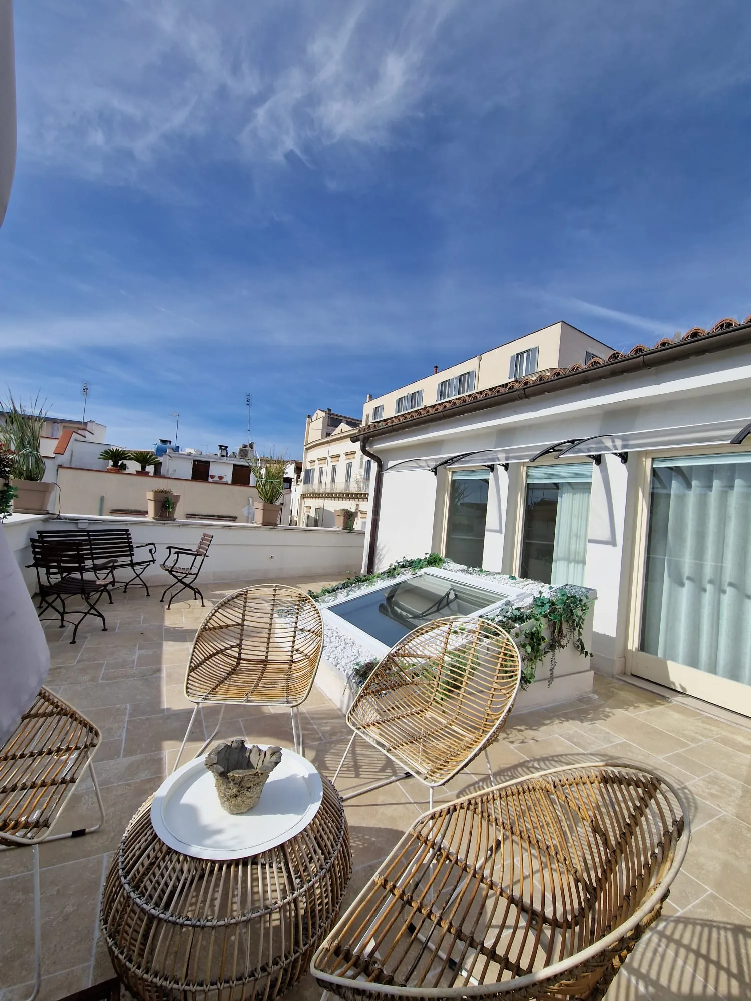 Terrazza sul tetto con poltroncine in rattan, tavolino tondo e vasca idromassaggio, affacciata sui tetti del centro di Andria